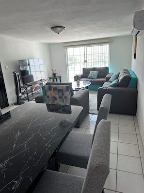 Una sala de estar moderna con una mesa de comedor, sofá y televisor.