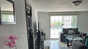 Ein Wohnzimmer mit einer Couch, einem Couchtisch, einem Fernseher und einer Topforchidee.
