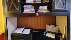 Een werkplek met een printer, boeken en kantoorartikelen.