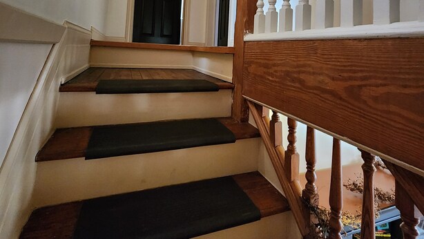 Een trap met houten treden en witte balustrades.
