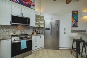 Une cuisine avec des armoires blanches, un réfrigérateur en acier inoxydable, un four à micro-ondes et une cuisinière.