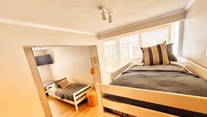 Ein modernes Schlafzimmer mit Etagenbett, Schreibtisch und großem Fenster.