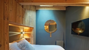 A wooden-paneled room with a bed, a round mirror, and a wall-mounted light fixture.