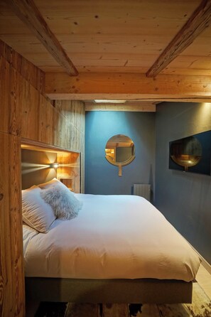 A wooden-paneled room with a bed, a round mirror, and a wall-mounted light fixture. - Warm Alpine Apartment 2BR 5P - Megeve (Megeve)