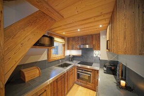 A kitchen with wooden cabinets, a stainless steel sink, a built-in oven, and a microwave. - Warm Alpine Apartment 2BR 5P - Megeve (Megeve)