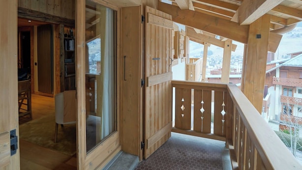 A wooden interior with a balcony, wooden flooring, and a view of the outside.