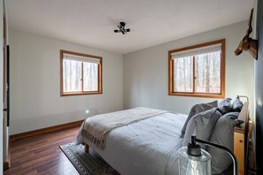 A bedroom with a bed, two windows, a ceiling fan, and a nightstand. - Secluded Chalet: Trails, EV charger, Game Room (Lancaster)