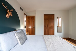 A bedroom with a bed, a wooden door, a mirror, and a wall-mounted deer head decoration. - Secluded Chalet: Trails, EV charger, Game Room (Lancaster)