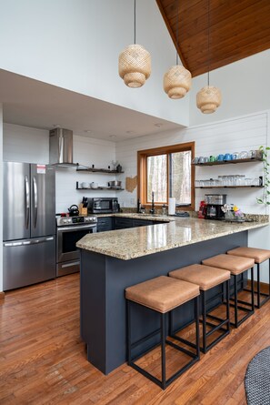 A modern kitchen with a large island, stainless steel appliances, and a wooden ceiling. - Secluded Chalet: Trails, EV charger, Game Room (Lancaster)