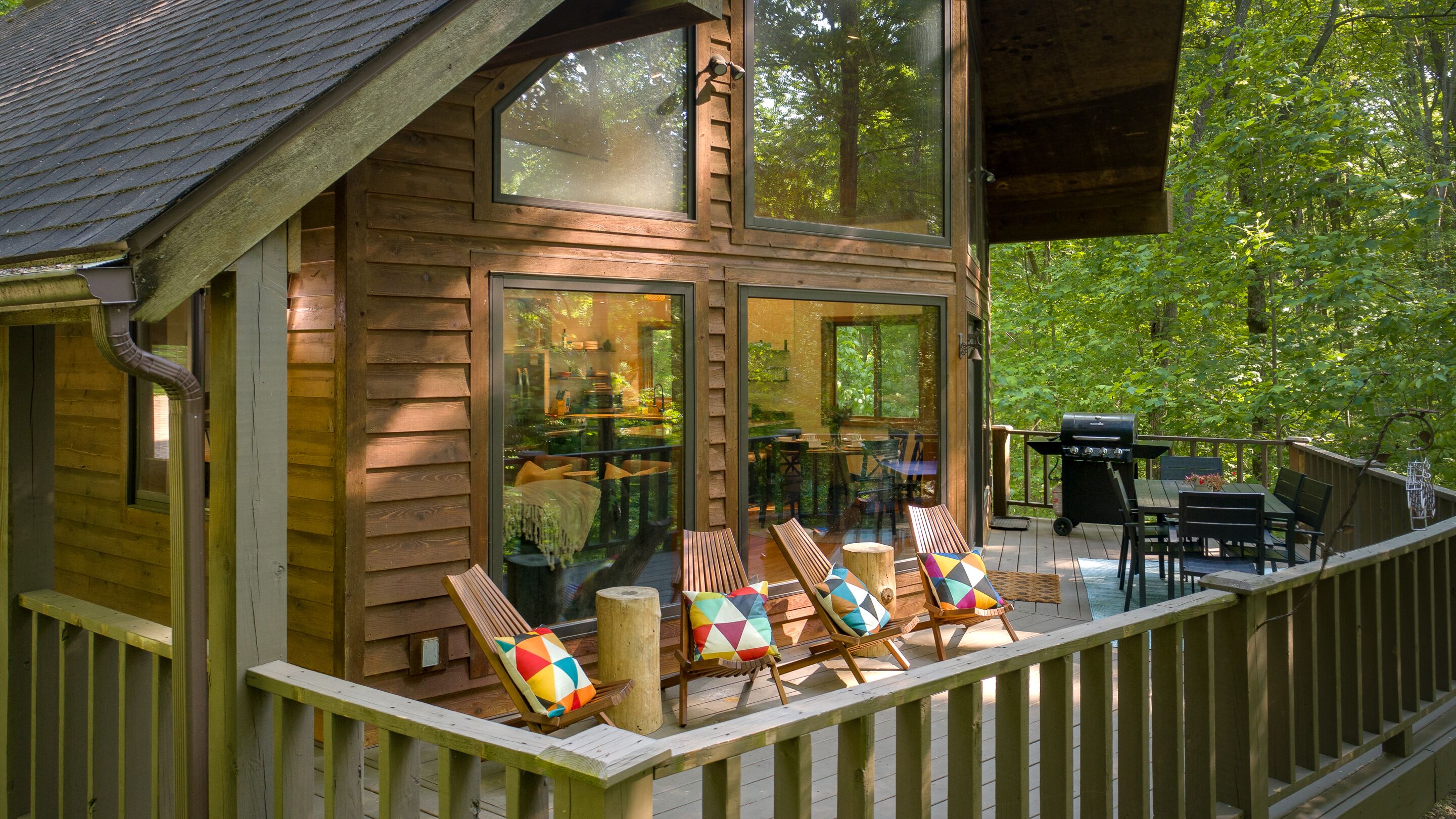 Eine Holzhütte mit einer Terrasse, Sitzgelegenheiten im Freien und einem Grill.