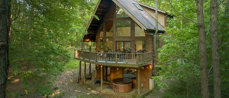A cabin with a balcony, a hot tub, and a deck area.