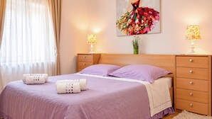A bedroom with a bed, two bedside tables, a nightstand, a dresser, a window with curtains, and a wall-mounted painting. - Awesome home in Solin (Solin)