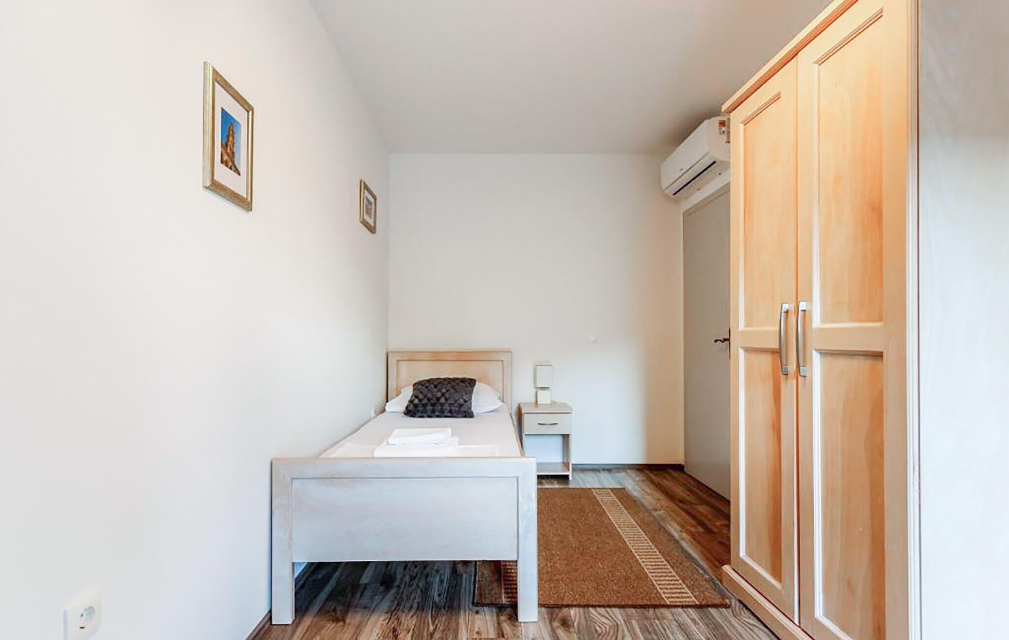 Une chambre à coucher comprenant un lit, une table de chevet, une armoire et un appareil de climatisation.