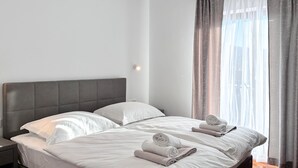 A hotel room with a large bed, two pillows, a nightstand, and a window with curtains. - Lovely home in Lozovac (Lozovac)