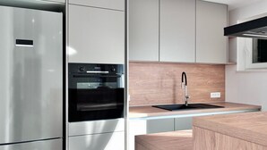 A modern kitchen with a built-in oven, stainless steel refrigerator, and a wooden countertop with a sink. - Lovely home in Lozovac (Lozovac)