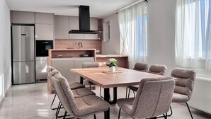 A modern kitchen with a dining area, including a wooden table and upholstered chairs. - Lovely home in Lozovac (Lozovac)