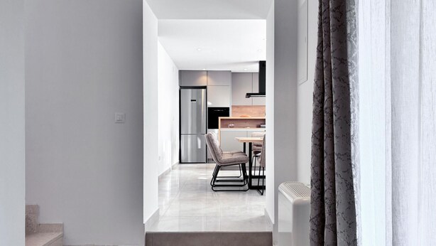 A modern kitchen with a refrigerator, stove, and dining area with chairs. - Lovely home in Lozovac (Lozovac)