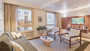 Ein modernes Wohnzimmer mit einer Couch, Sesseln, einem Couchtisch und einem Fernseher.