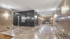 Eine moderne Hotelhalle mit einer Rezeption, einem Schild, das auf das achteckige Muster des Bodens hinweist, und einem sauberen, gefliesten Boden.