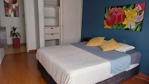 Ein Schlafzimmer mit einem Bett, einem Kleiderschrank, einem Gemälde und einer Zimmerpflanze.