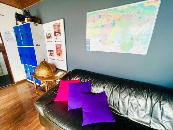 A room with a black leather sofa, a globe, and a map on the wall.