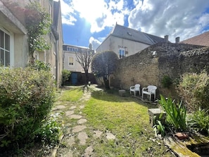 A stone wall, a grassy courtyard, and a building with a door.