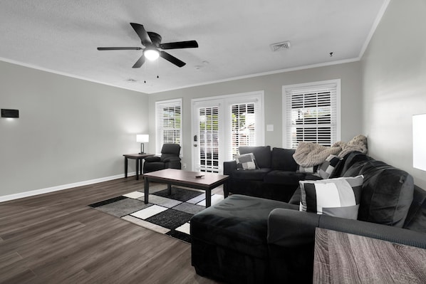 A living room with a ceiling fan, a sofa, a coffee table, and a rug.