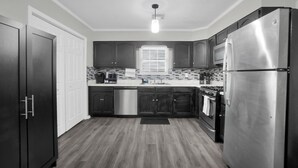 Una cocina moderna con armarios oscuros, electrodomésticos de acero inoxidable, un microondas y un lavavajillas.
