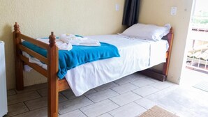 Una cama individual con estructura de madera, ropa de cama blanca y una colcha azul.