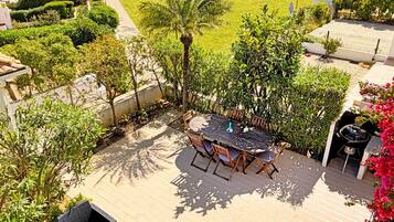 A patio with a table and chairs, a barbecue grill, and a pool in the background.