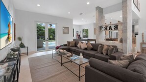 Ein modernes Wohnzimmer mit einer Couch, einem Couchtisch und Blick auf einen Pool durch Glastüren.