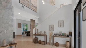 Ein großzügiger Innenraum mit hoher Decke, einer Treppe und einem Essbereich.