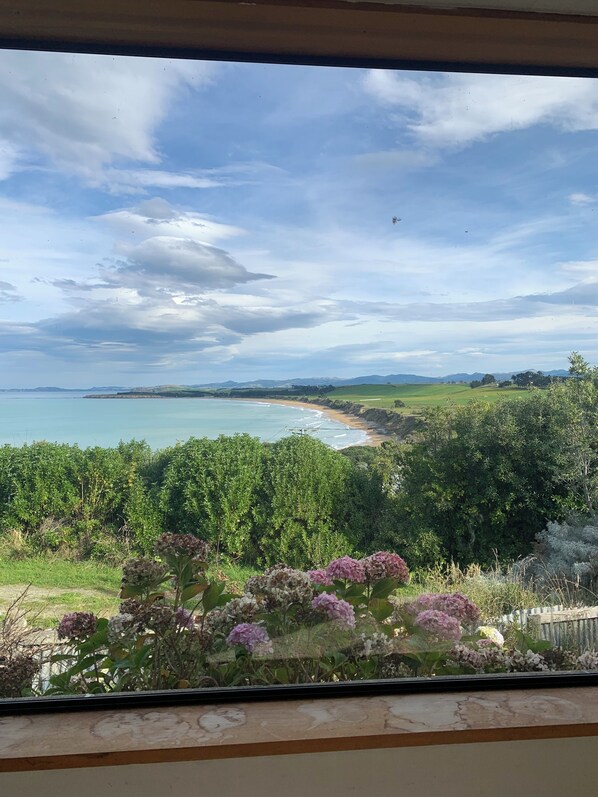 A coastal landscape with a view of the sea, greenery, and a clear sky.