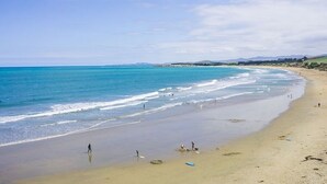 Une plage dotée d’un large rivage sablonneux, de vagues douces et d’un ciel dégagé.
