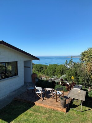 En terrasse med udendørs møbler, en hvid bygning og havudsigt.