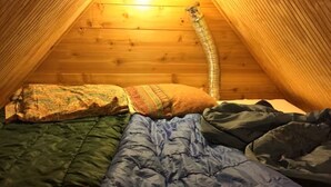 Um quarto de sótão pequeno e acolhedor, com teto inclinado e paredes de madeira.