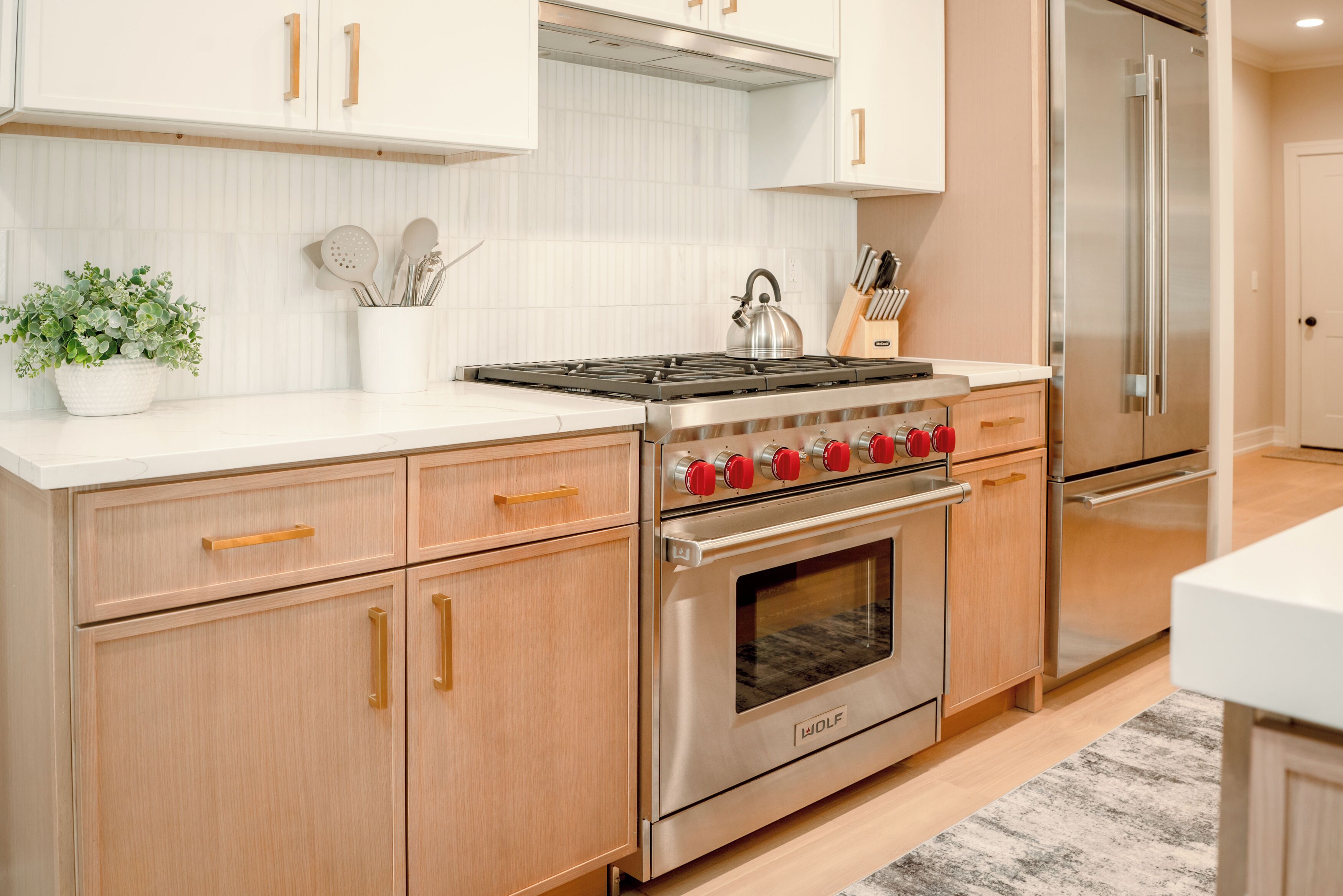 A modern kitchen with stainless steel appliances, wooden cabinets, and a white countertop.