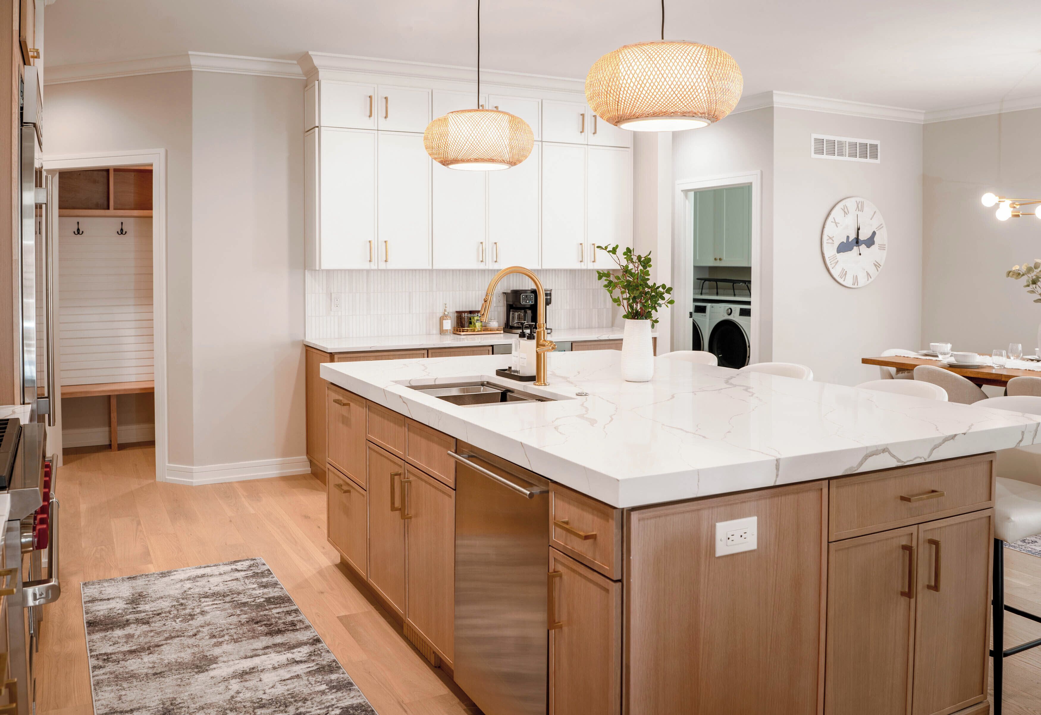 A modern kitchen with white cabinets, a marble countertop, a built-in dishwasher, and a large island.