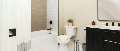 A bathroom with a bathtub, toilet, and vanity.
