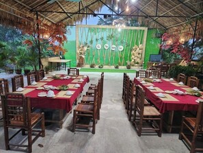An outdoor dining area with tables set for a meal, surrounded by wooden chairs. - Dong Que Homestay - Hostel (Ha Giang)