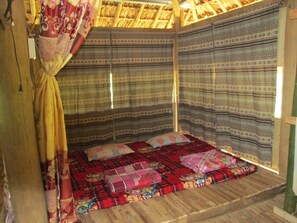 A room with a bed, patterned curtains, and a wooden floor. - Dong Que Homestay - Hostel (Ha Giang)