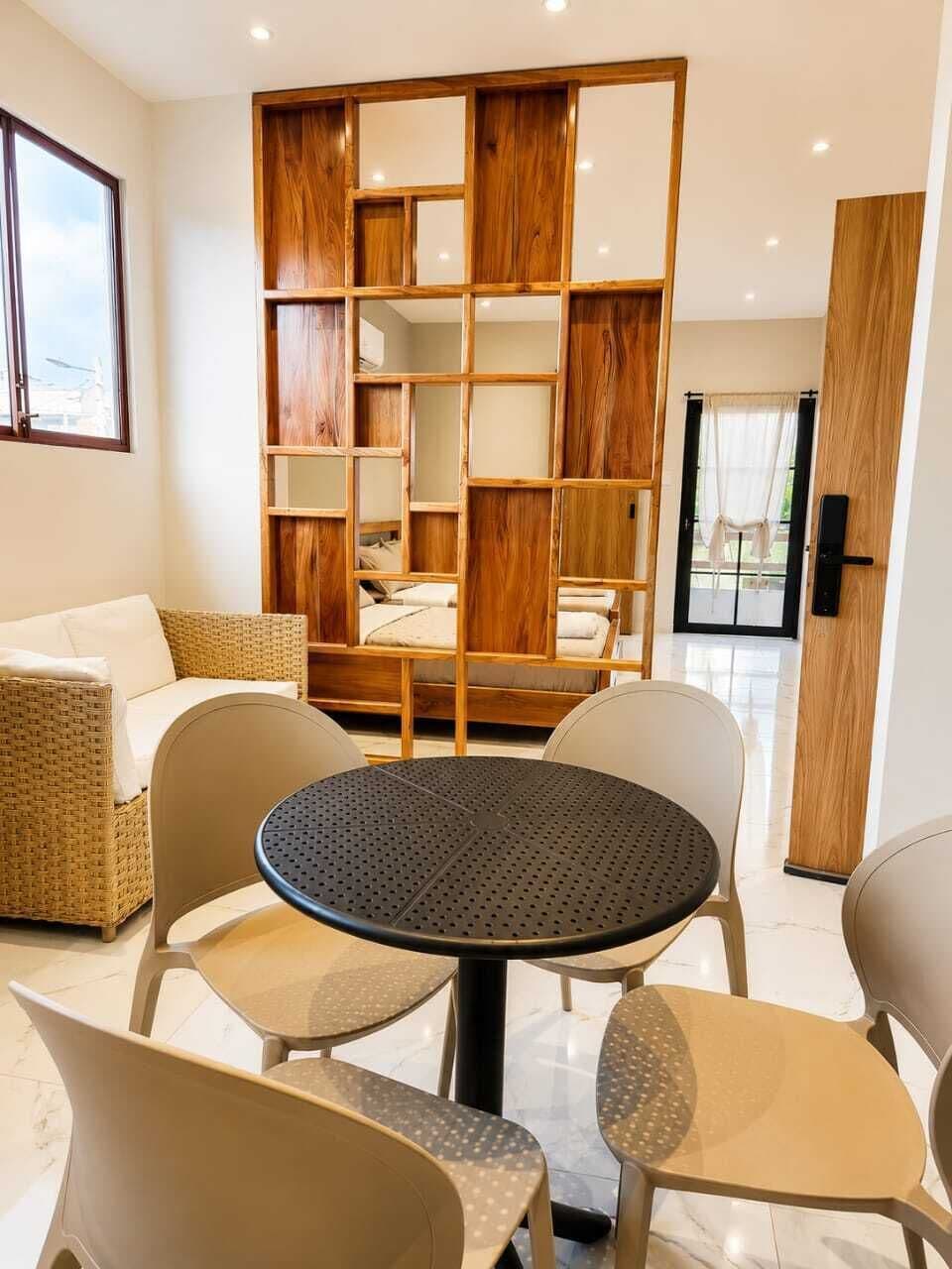 Een moderne kamer met een ronde tafel, vier stoelen, een bank en een houten boekenkast.