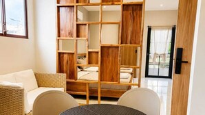 A modern room with a round table, four chairs, a sofa, and a wooden bookshelf.