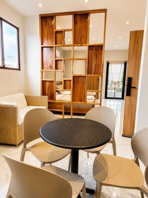 A modern room with a round table, four chairs, a sofa, and a wooden bookshelf. - Modern and cozy with excellent location (San Cristóbal)