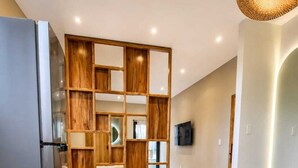 A modern kitchen with a built-in refrigerator, wooden shelving, and a dining area with a round table and chairs.