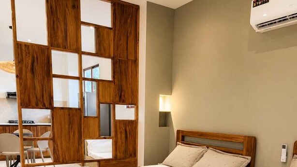 A hotel room with two wooden beds, a desk, a chair, and a wall-mounted air conditioner.