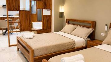 Een hotelkamer met twee houten bedden, een bureau, een stoel en een luchtverkoeler aan de muur.