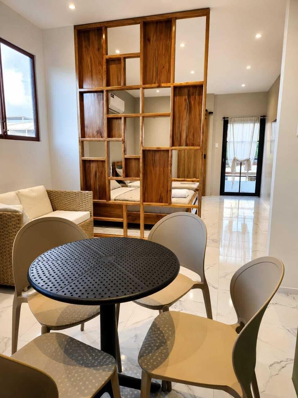 Een moderne kamer met een ronde tafel, vier stoelen, een bank en een houten boekenkast.