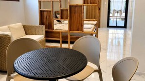 A modern room with a round table, four chairs, a sofa, and a wooden bookshelf.
