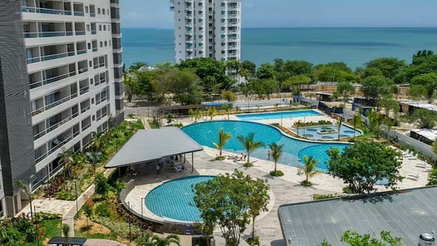 Un hotel amb diverses piscines, una zona de seients coberta i vistes a l'oceà.